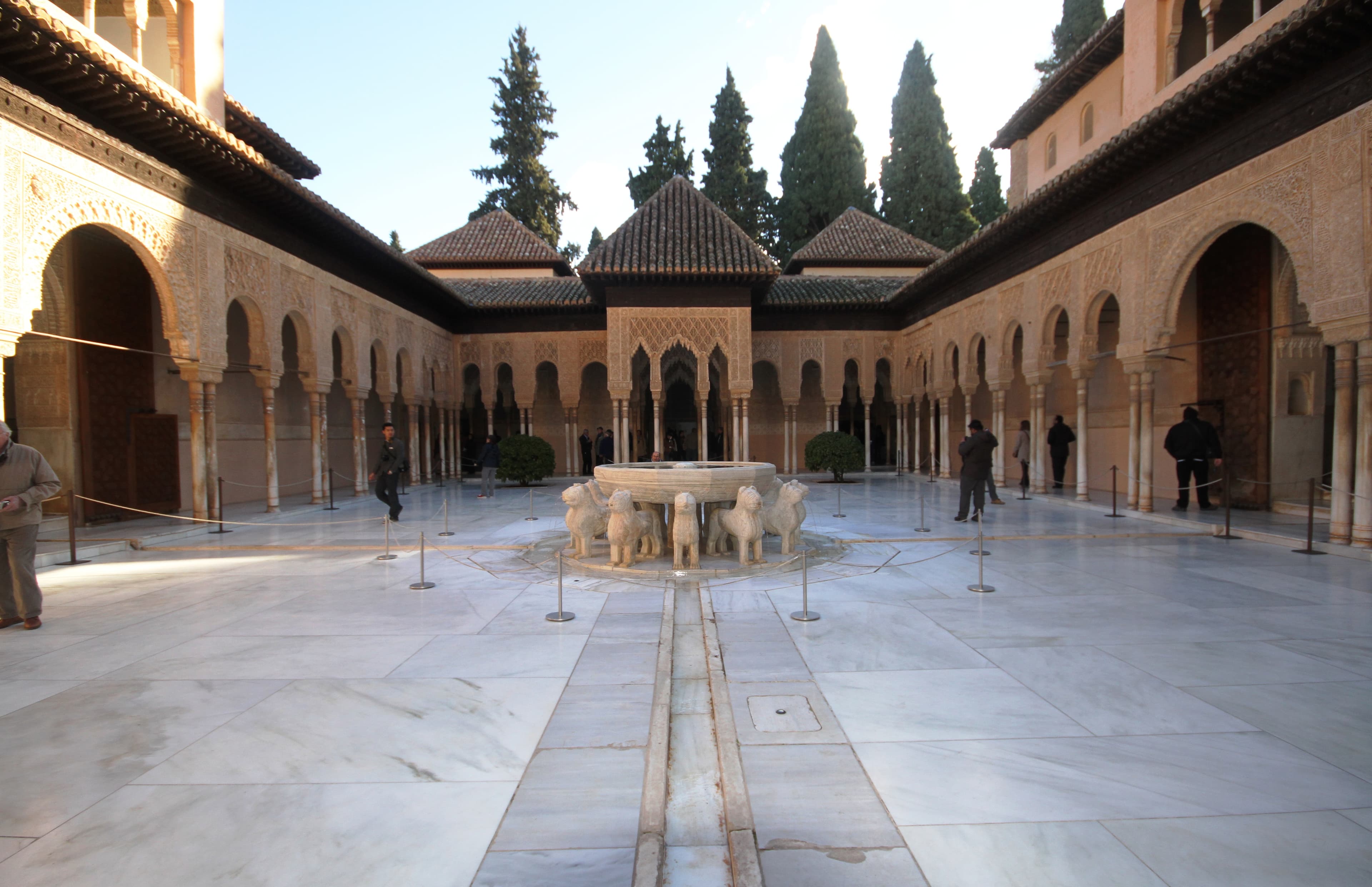 Patio de los Leones de la Alhambra con su fuente central rodeada de columnas de mármol y arcos de filigrana nazarí.