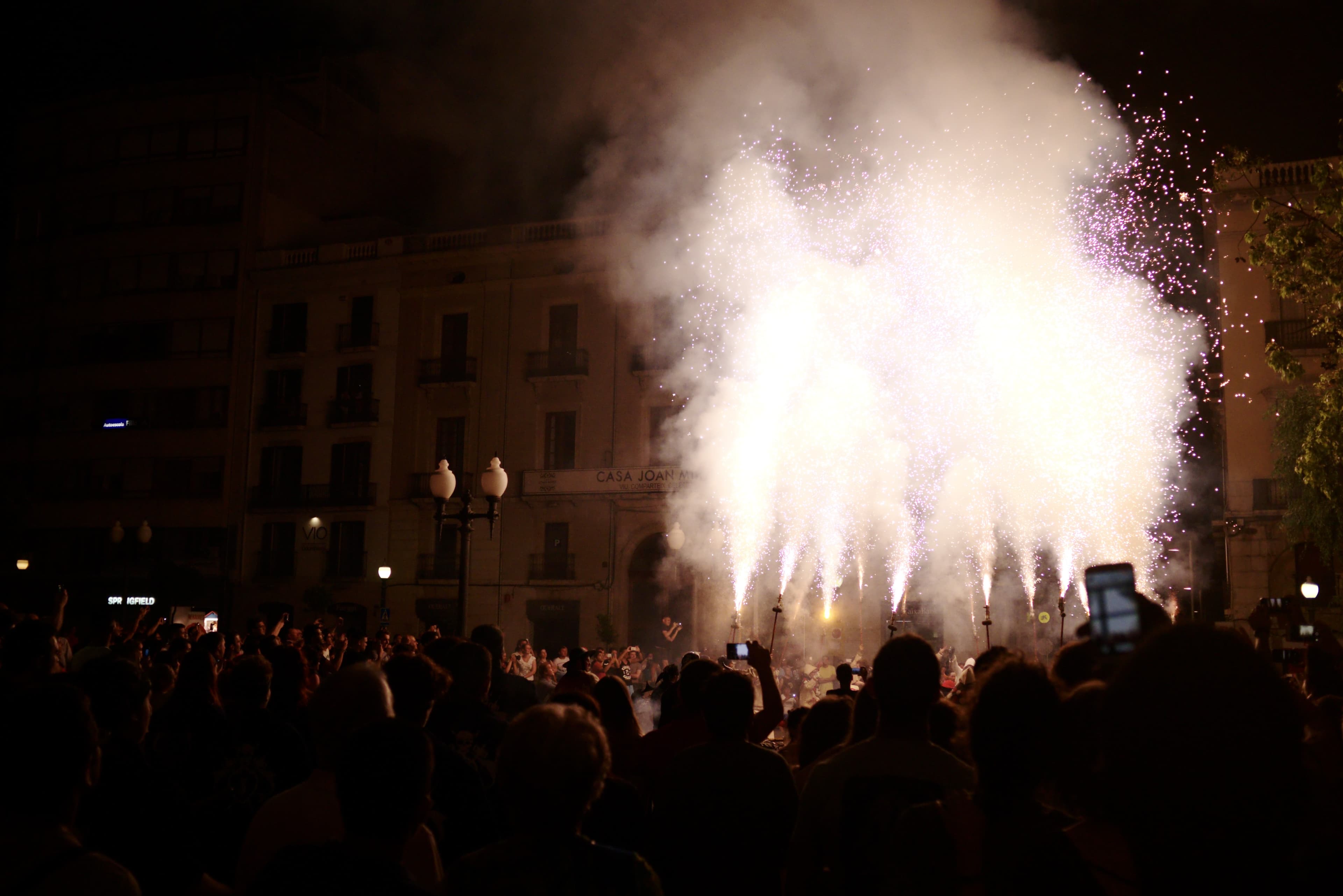 Espectáculo de fuegos artificiales y correfoc durante la Nit de Sant Joan en Tarragona, con una multitud reunida frente a un edificio histórico iluminado por las chispas