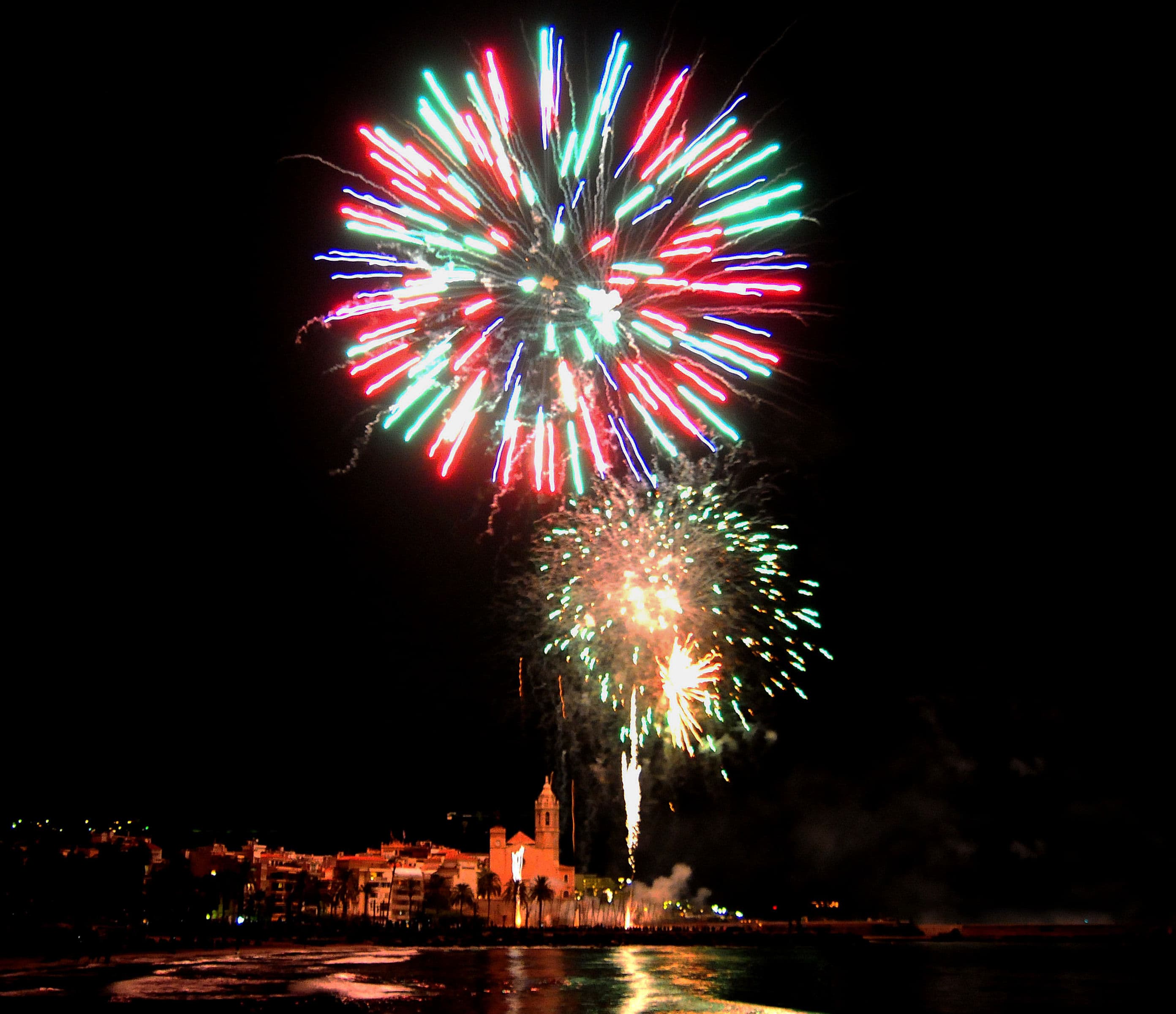 Fuegos artificiales nocturna durante la Festa Major de Sant Bartomeu en Sitges, con la iglesia de Sant Bartomeu i Santa Tecla al fondo