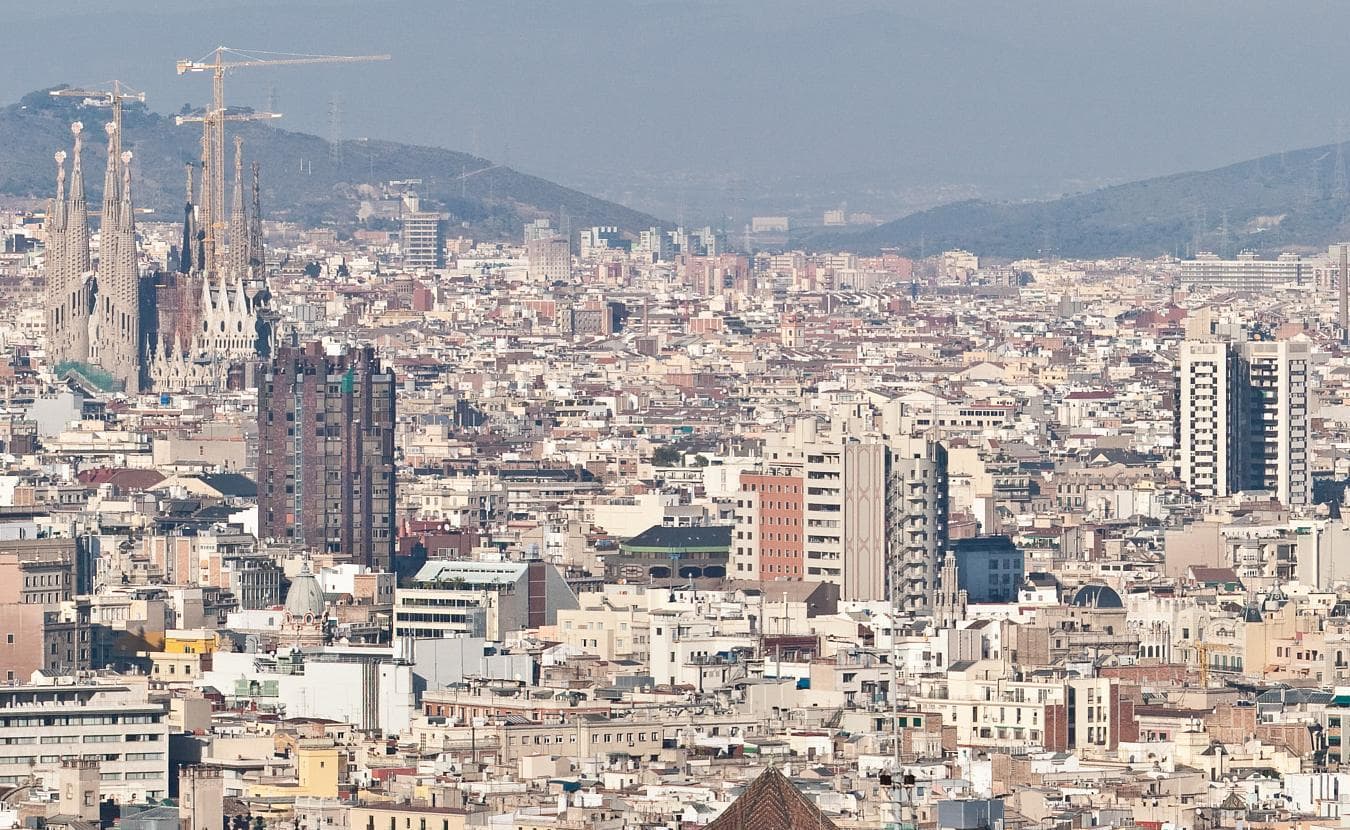 Panorámica del skyline de Barcelona desde lo alto, con la trama del Eixample, las torres de la Sagrada Família y el mar al fondo