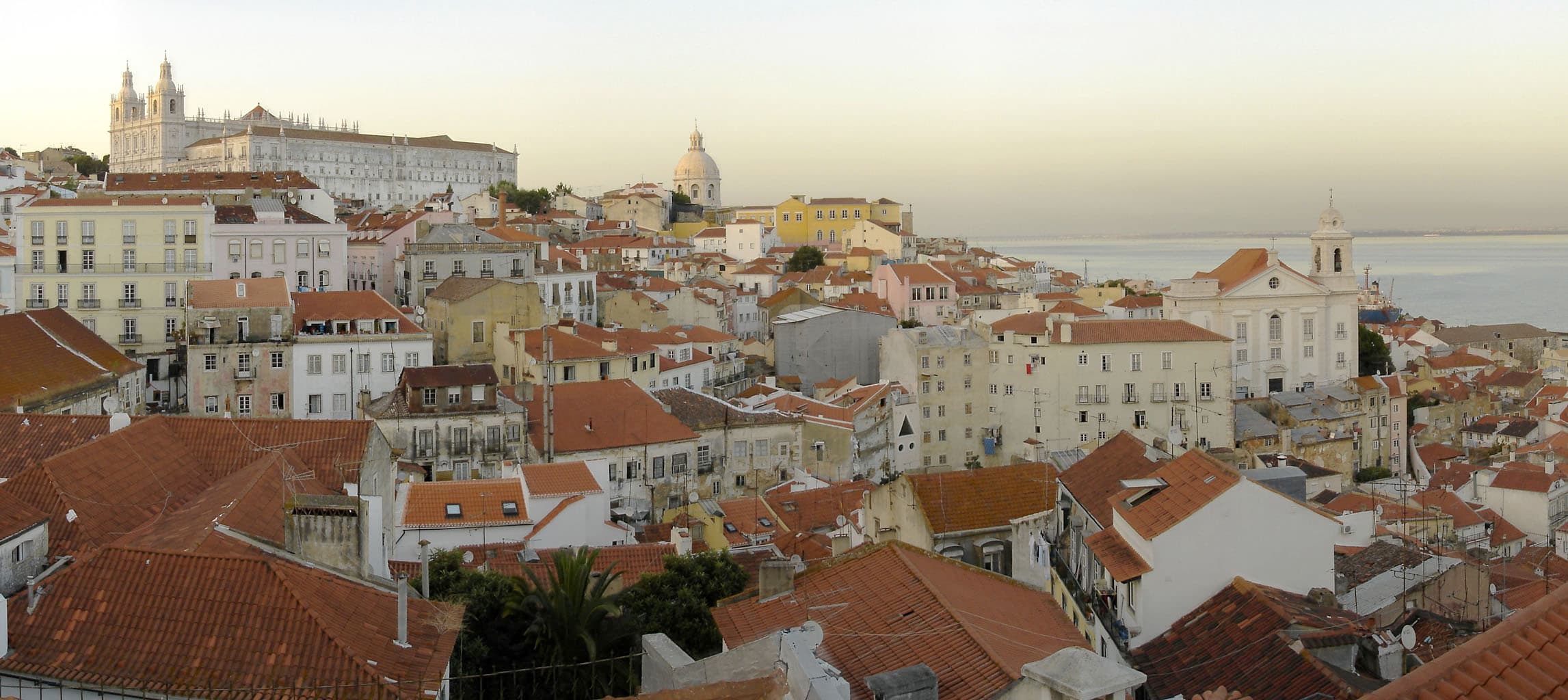 Callejuela empedrada y empinada del barrio de Alfama entre fachadas de azulejos