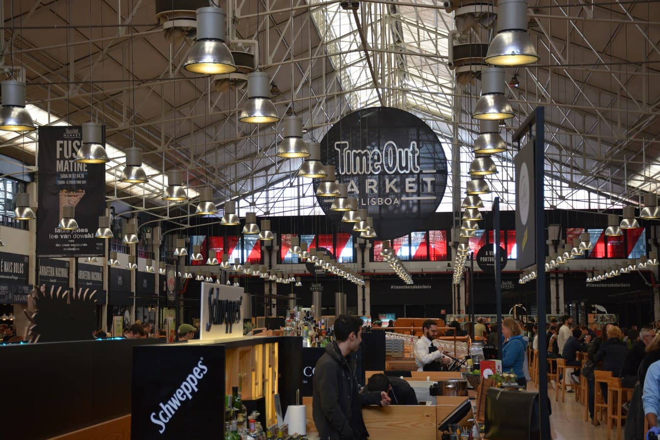 Visitantes con bebidas en las mesas comunales del food court del Time Out Market de Lisboa