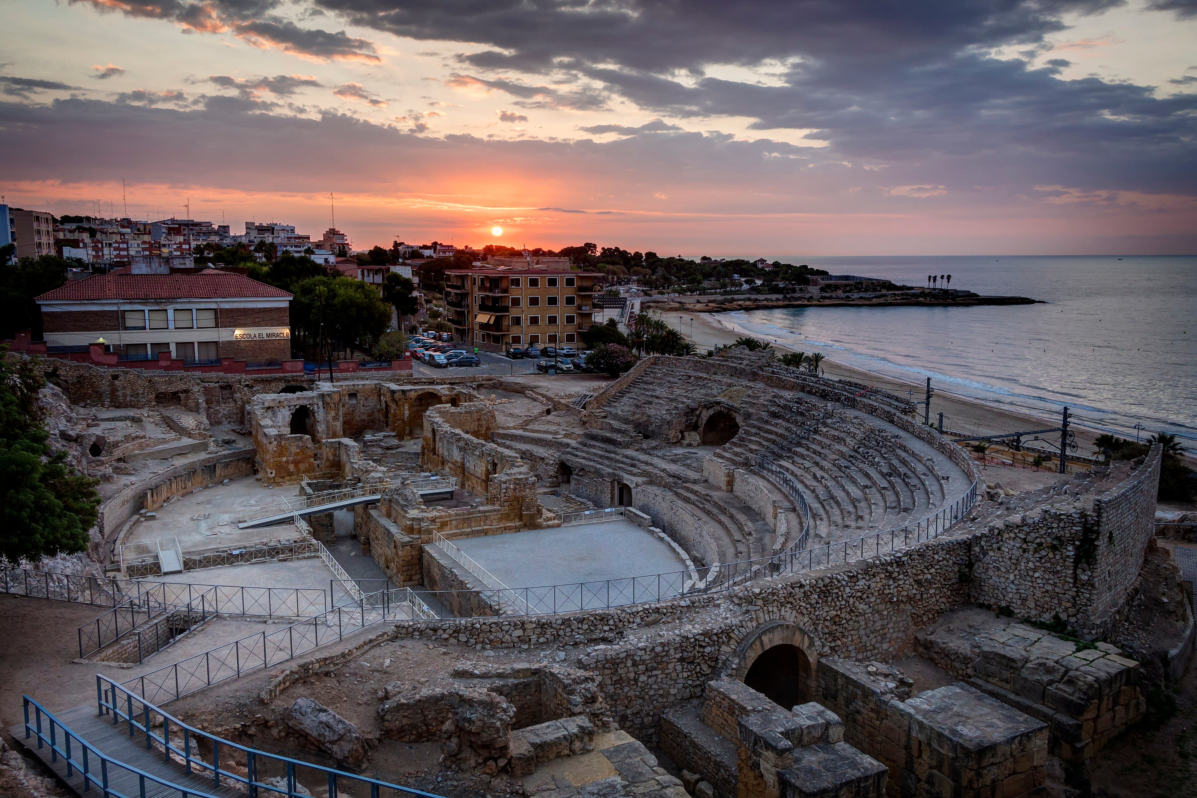 El anfiteatro romano de Tarragona asomado al mar Mediterráneo, con las gradas de piedra excavadas frente al agua