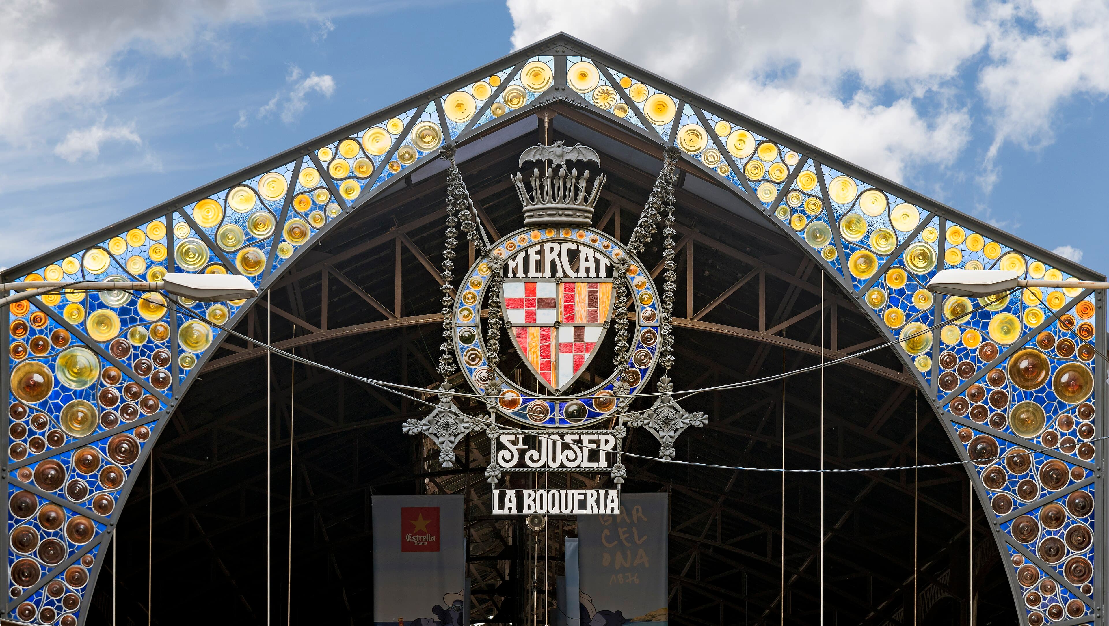 La entrada modernista del Mercat de Sant Josep de la Boqueria desde la Rambla, con su letrero de vidrieras de colores y el escudo coronando el arco